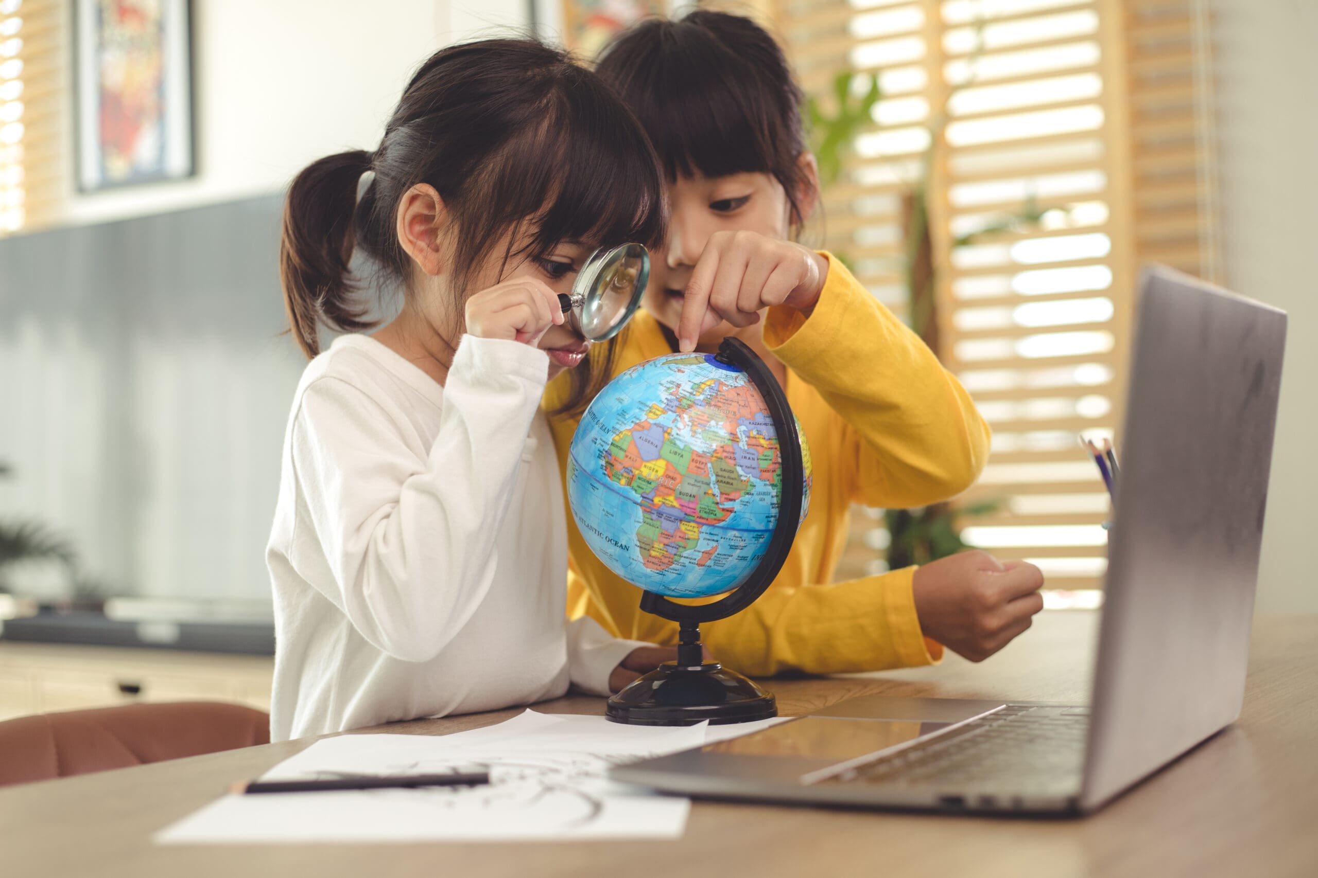 Two young girls studying geography with a world globe.